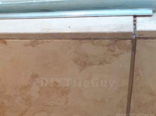 cracked grout joints from water damage. travertine tiles