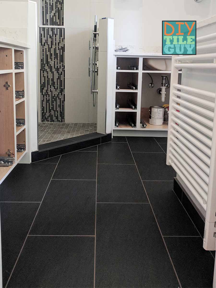 Black 12x24 tiles are installed vertically with a 50% offset pattern on a bathroom floor