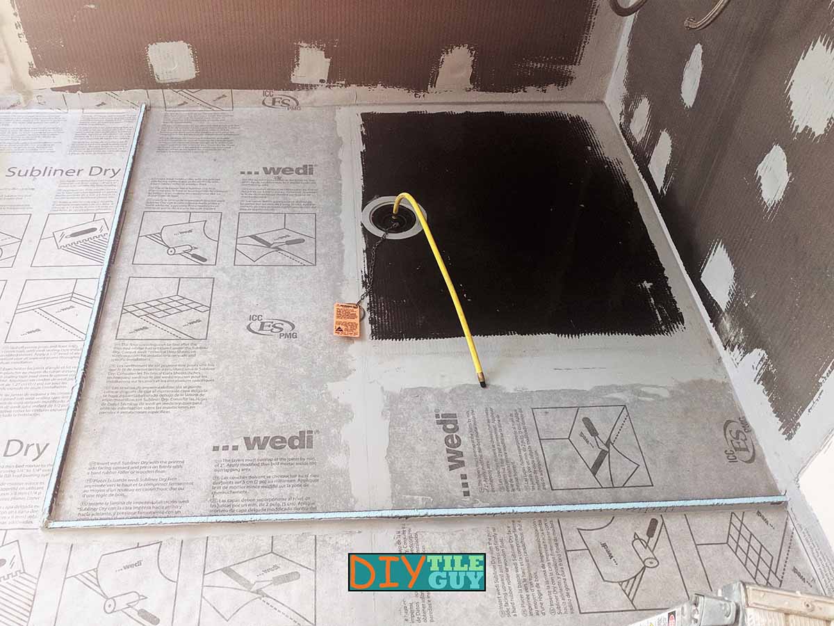 Wedi Ligno curbless shower pan installed with Subliner Dry used to extend the waterproofing to outside the wet area. A temporary curb was installed to allow for a flood test prior to tile installation.